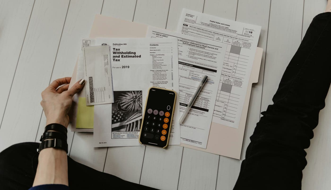 Financial statements, calculator and pen laid out on a white desk