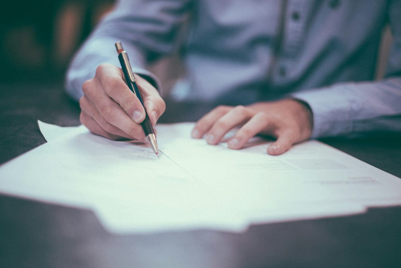 Hand signing booking documents at a desk